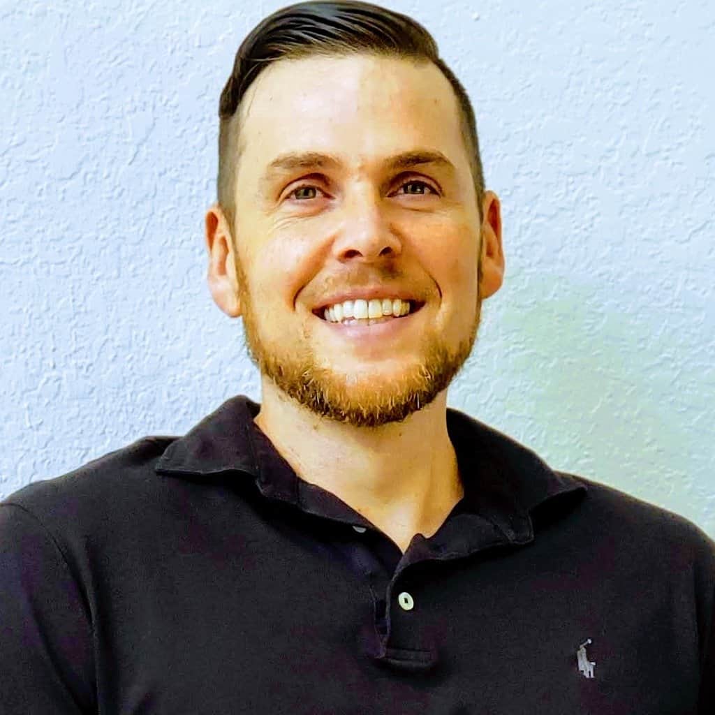 Man with a friendly smile posing for a photograph against a plain background.