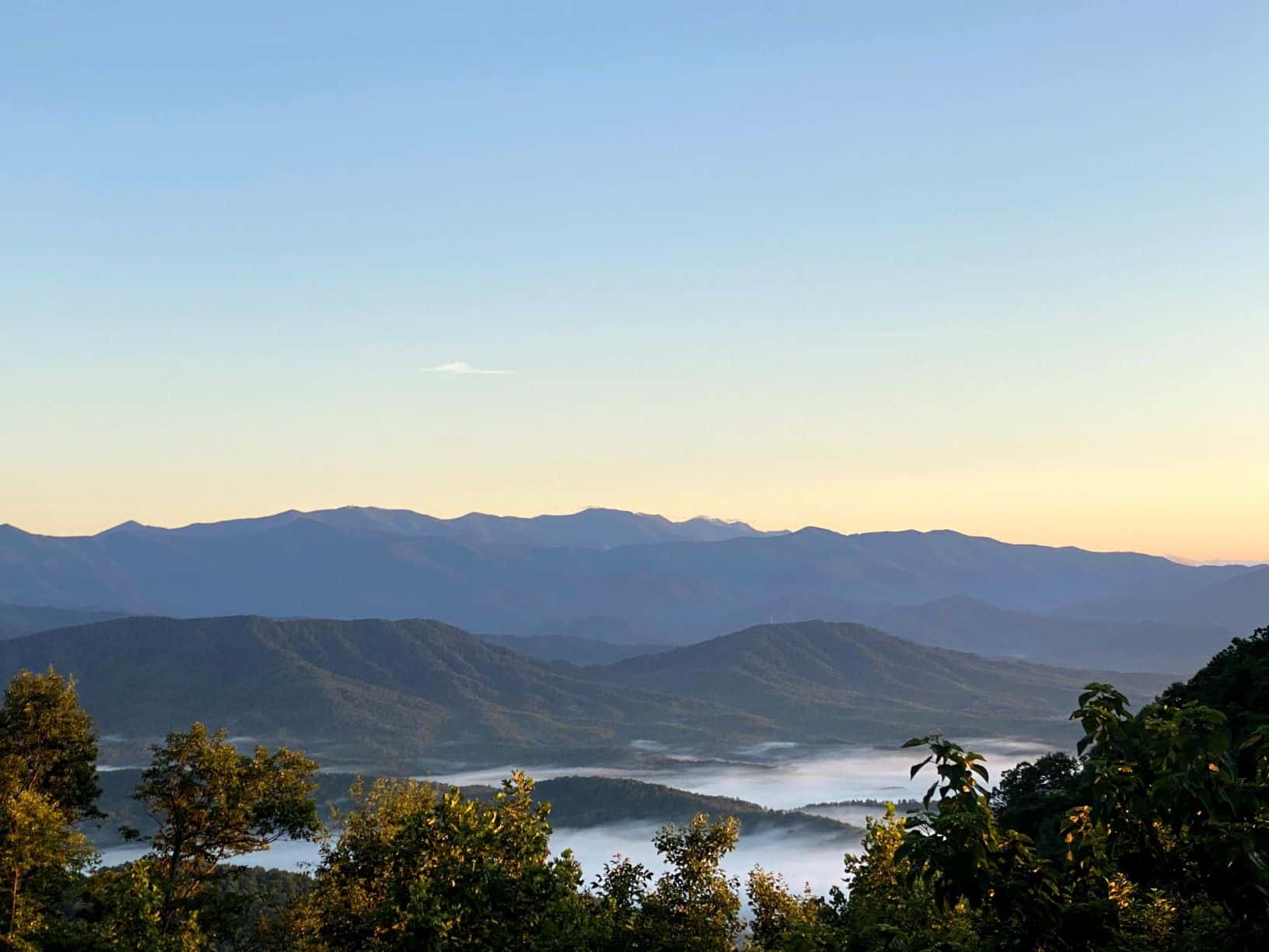 Early morning tranquility over a misty mountain valley as the first light of day graces the horizon.