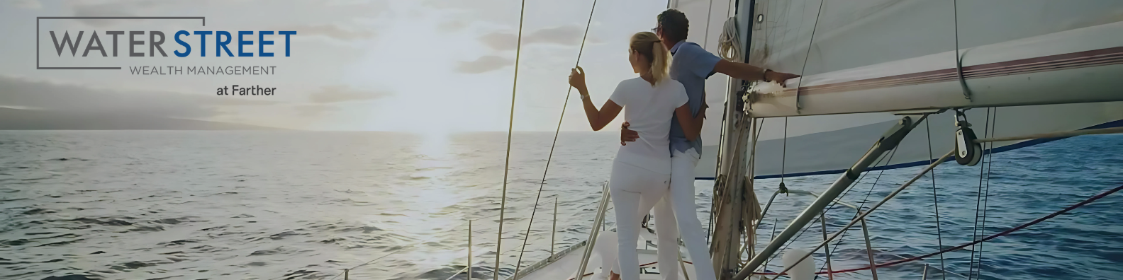 A couple stands on a sailboat at sunset, looking out over the ocean. The logo 